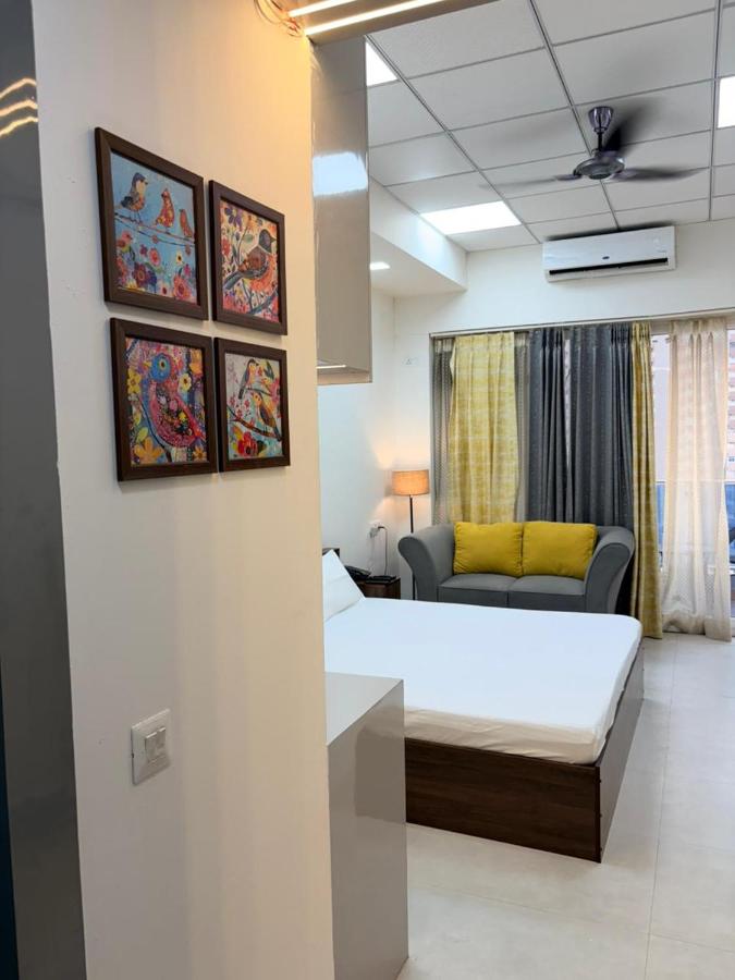 Deluxe studio entrance view with framed bird paintings, the bed, a sofa and full-length curtains