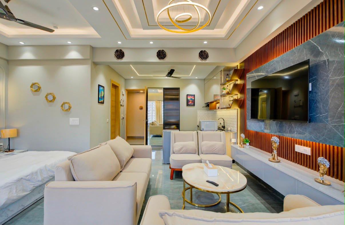 Open-plan studio showing the living area, TV wall and kitchenette with the bed at the left